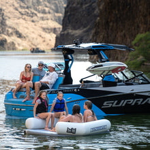 Group of people on a blue and black Supra boat with mountains in the background