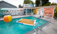 Pool area with inflatable basketball court, colorful ball, and poolside building.