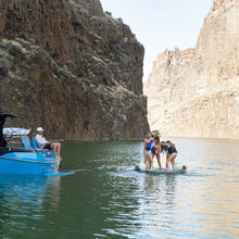 People on a raft in a narrow canyon with cliffs on either side.