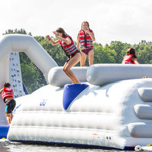 People on an inflatable water park structure with trees in the background
