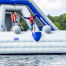 Two children on an inflatable water toy in the water with trees in the background