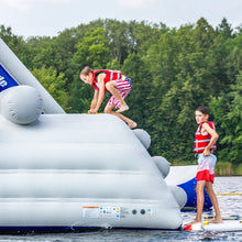 Two children on an inflatable water toy in a lake with trees in the background