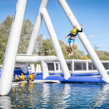 Person on an inflatable water park structure with trees and clear sky in the background