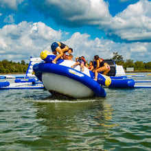 People on Aquaglide Rockit Circular Water Rocker in a lake with a blue sky and clouds.