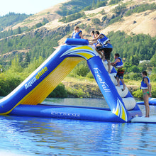 Inflatable water slide with 'Aquaglide' branding on a body of water with mountains in the background.
