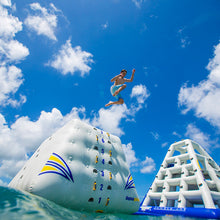 Person jumping off an inflatable water slide with a blue sky and clouds in the background