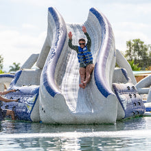 Person sliding down a large inflatable water slide in a pool