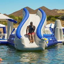 Person sliding down a large inflatable water slide in a desert setting with mountains in the background.