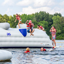People on an inflatable water park structure in a lake with trees in the background