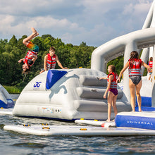People on an inflatable water park structure with a person doing a flip.
