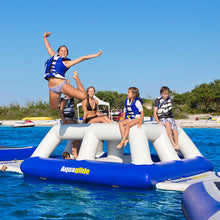 Children playing on an inflatable water toy in a pool with clear blue sky.