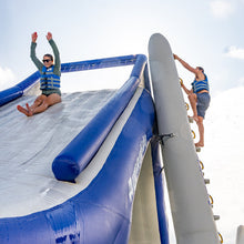 Two people on an inflatable water slide with a clear sky background