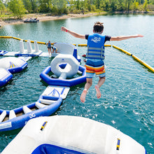 Child jumping off an inflatable structure into a lake with other similar structures.