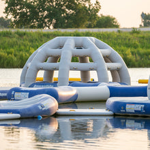 Inflatable water park structure on a lake with greenery in the background
