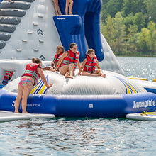 Children on an inflatable water toy with Aquaglide branding in a lake setting.