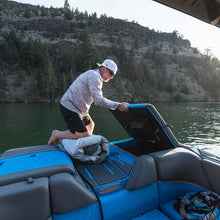 Man on a boat in a lake with a mountainous background