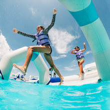 Two children playing on an inflatable water slide in a pool.