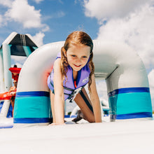 Child in a life jacket on an inflatable water slide with a blue sky background