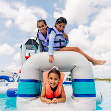 Children on an inflatable structure at a water park with a clear blue sky.