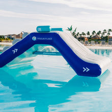 Inflatable water slide with Penguin Plunge branding in a pool setting.