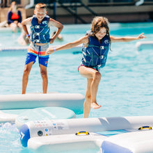 Two children in life vests playing in a pool with inflatable toys.
