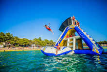 Inflatable water slide in a lake with people enjoying the activity on a clear day.