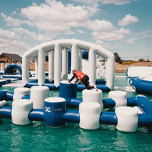 Inflatable water park with a person in a red jacket interacting with the structure on a sunny day.