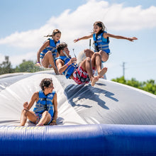 Children playing on an inflatable slide with life vests in a sunny outdoor setting