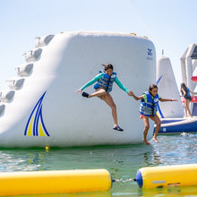 Two children playing on an inflatable water structure in a pool.