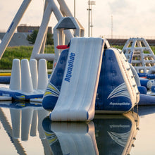 Inflatable water slide with 'Aqua glide' branding on a reflective water surface.