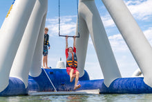 Children playing on a large inflatable structure with a blue sky and water background