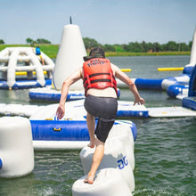 Person in a life jacket walking on floating platforms in a water park