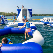 Children playing on an inflatable water park in a lake on a sunny day.