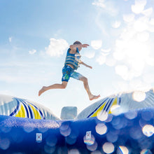 Person jumping off a blue inflatable structure with a clear sky background