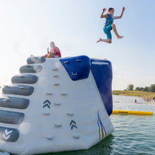 Child jumping off an inflatable water slide into a lake with 'Aquaglide' branding.