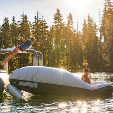 Child jumping off Aquaglide Launch Bag into a lake with trees in the background