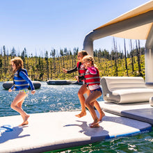 Children playing on Aquaglide Full Deck 15.0 with a scenic background of trees and water.
