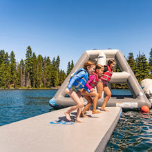 Children on Aquaglide Full Deck 15.0 in a lake with trees in the background