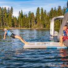 Children playing on an inflatable platform in a lake with trees in the background