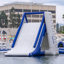 Inflatable water slide with blue and white design on a pool, building in the background