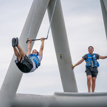 Two people on a swing set with a clear sky background