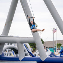 Person on a trapeze at an outdoor playground with a clear sky.