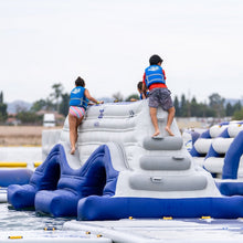 Children playing on an inflatable water obstacle course with life vests.