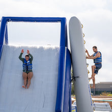 Person sliding down an inflatable water slide with another person at the top.