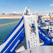Inflatable water slide with Aquaglide branding near a body of water on a sunny day.