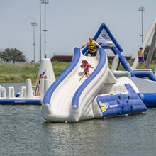 Inflatable water slide with people on a lake.