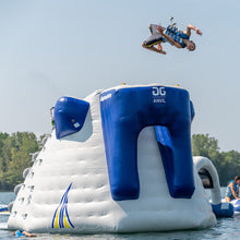 Person performing a jump off an inflatable water obstacle course on a sunny day.