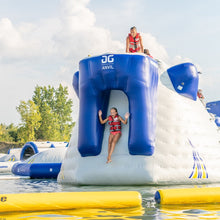 Two people on an inflatable water structure with 'AG Anvil' branding in a water park setting.