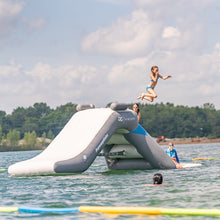 Inflatable water slide on a lake with people enjoying the activity