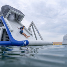 Person sliding down an inflatable water slide in a lake